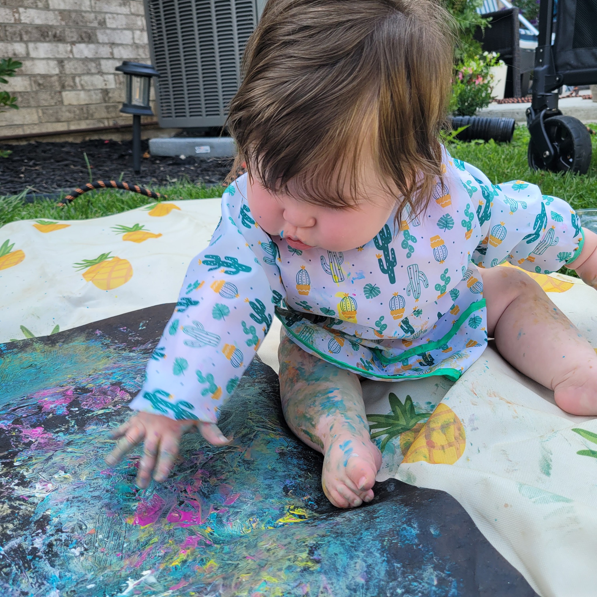 Baby enjoying messy paint play outdoors