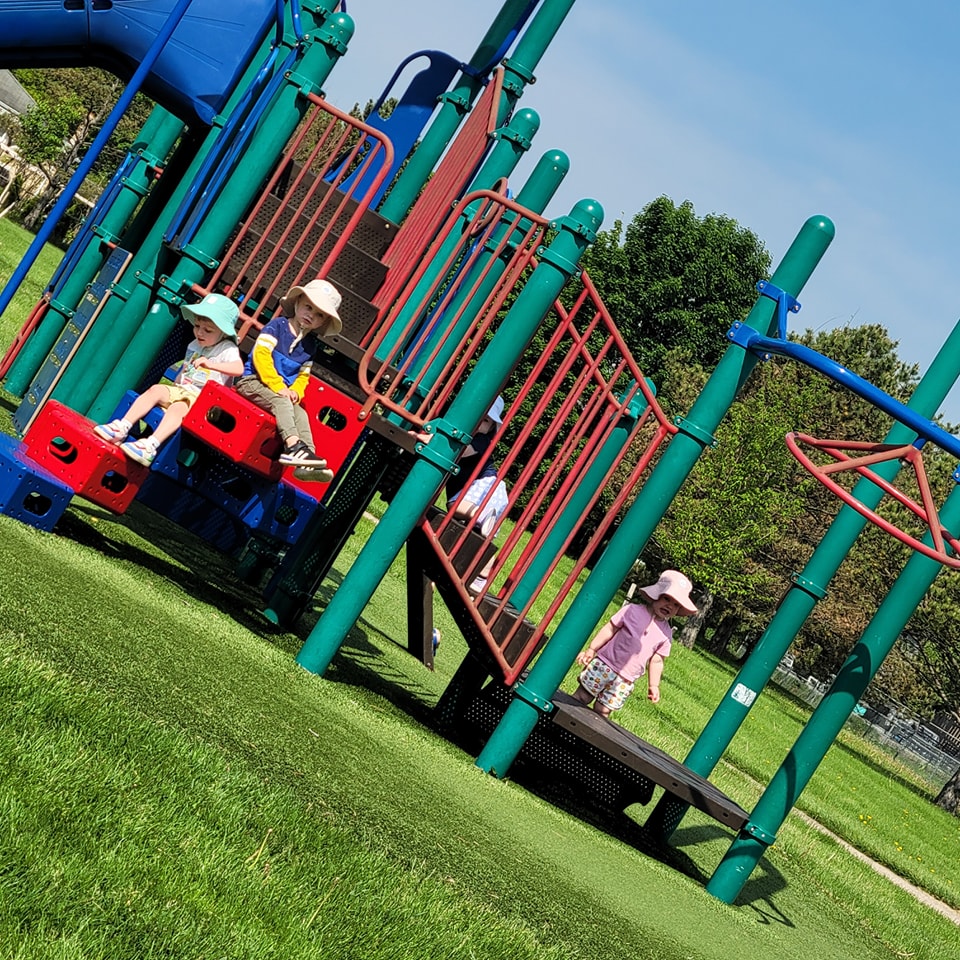 Children in sun hats playing on colourful playground equipment